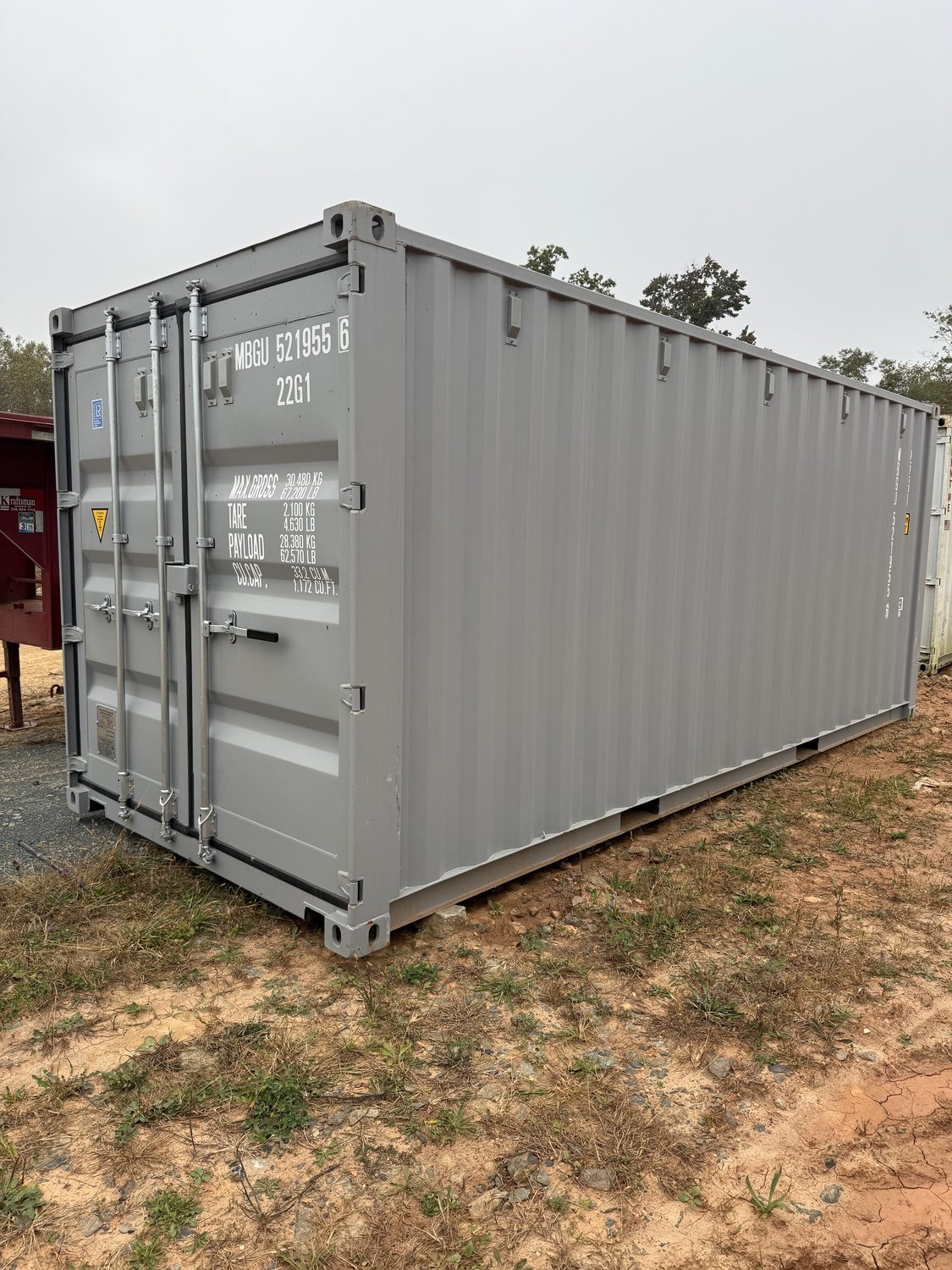 Slate-gray 20-foot shipping container set on a residential gravel pad